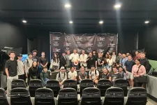 Thumbnail for Large group of diverse young adults and speakers posing in front of a Shrimp Tank branded backdrop in auditorium.