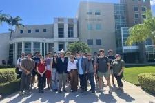 Thumbnail for Group of students and faculty standing outside Phil Smith Hall at the College of Business on a sunny day.