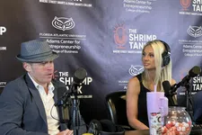 Thumbnail for Two podcast hosts speaking into microphones during a recording at The Shrimp Tank studio.