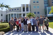 Thumbnail for Group of diverse students and faculty posing outside Phil Smith Hall College of Business on a sunny day.