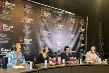 Thumbnail for Four hosts wearing headphones speaking into microphones at The Shrimp Tank podcast panel with branded backdrop