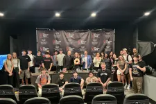 Thumbnail for Large group of diverse people posing in front of The Shrimp Tank backdrop in a studio setting with chairs in foreground.