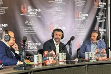 Thumbnail for Three men wearing headphones sitting at a podcast table with microphones and shrimp tanks beside them.