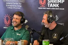 Thumbnail for Two men wearing headphones recording a podcast at a table with microphones and drinks in front of a Shrimp Tank backdrop.