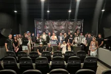 Thumbnail for Large group of people posing for a photo in a black room with theater seats and a Mike Nebelson campaign sign