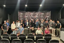 Thumbnail for Group photo of diverse participants posing at The Shrimp Tank event with branded backdrop and professional lighting.