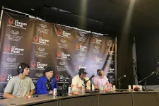 Thumbnail for Four men with headphones sitting at a podcast panel table with microphones and branded backdrop of The Shrimp Tank event
