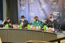 Thumbnail for Four people wearing headphones at a podcast table with The Shrimp Tank banner and microphones