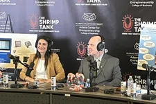Thumbnail for Two people with headphones speak into microphones hosting The Shrimp Tank podcast at Florida Atlantic University event