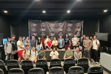 Thumbnail for Group of diverse young adults posing in front of The Shrimp Tank banner inside a conference room with empty chairs.