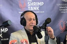 Thumbnail for Man wearing headphones speaking into microphone during The Shrimp Tank podcast with shrimp candy jar and Celsius drink cans on desk