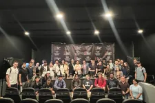 Thumbnail for Group photo of diverse people posing in front of a Shrimp Tank event backdrop with studio lighting.