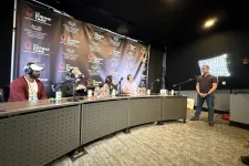 Thumbnail for Panel of four judges seated with microphones facing a standing presenter in a podcast studio with The Shrimp Tank backdrop