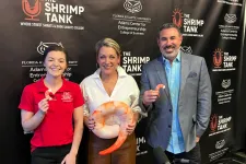 Thumbnail for Three people posing in front of The Shrimp Tank backdrop holding large shrimp props in a podcast studio setting
