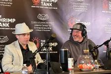 Thumbnail for Two men podcasting at a table with microphones and The Shrimp Tank backdrop from Florida Atlantic University.