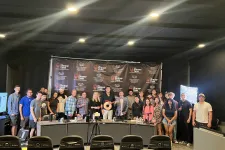 Thumbnail for Group photo of diverse people standing behind a table with a Shrimp Tank backdrop and bright studio lights