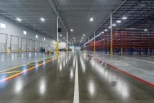 Thumbnail for Spacious industrial warehouse with empty shelving units and polished concrete floors under bright LED lighting.