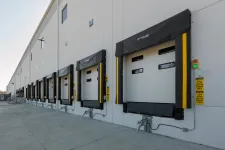 Thumbnail for Row of modern loading dock doors with protective seals on industrial warehouse exterior under clear sky.