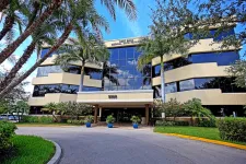Thumbnail for Modern three-story medical arts pavilion with palm trees and a reflective glass facade under a blue sky.