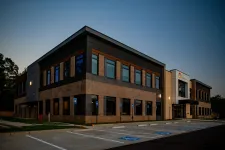 Thumbnail for Modern two-story office building with brick and glass exterior at dusk with empty handicap parking spaces