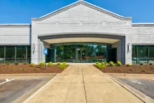 Thumbnail for Modern commercial building front with wide entrance, large windows, and clear blue sky.