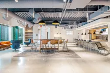 Thumbnail for Modern office lounge with a long table, bar stools, comfortable seating, and industrial ceiling design