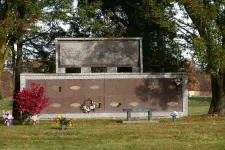 Thumbnail for a stone building with a bench and a child walking by it