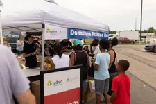 Thumbnail for Community members donate goods at a Telhio Credit Union donations booth outdoors under a white tent.