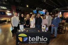 Thumbnail for Group of professionals standing behind a Telhio Credit Union promotional table in a bar setting.