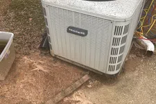 Thumbnail for AC Preventative Maintenance in Tucker, Atlanta by The Air Company of GA. Outdoor Frigidaire air conditioner unit with a red Milwaukee drill on top beside a brick wall and garden area.