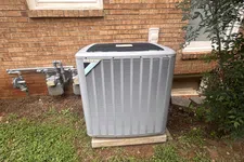 Thumbnail for AC Repairs in Tucker Atlanta by The Air Company of GA. Outdoor Daikin air conditioning unit installed beside brick house wall with grass and shrubbery.