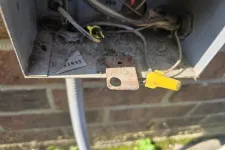 Thumbnail for Close-up of an open outdoor electrical junction box with wires, wire connectors, and rusted metal components.