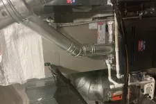 Thumbnail for Industrial furnace and ductwork system in a utility basement with metal vents and pipes.