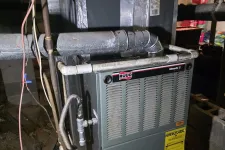 Thumbnail for Ruud furnace unit with attached ductwork and piping in a basement setting with wiring visible.