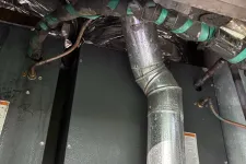 Thumbnail for Metal ductwork and insulated pipes connected to a large furnace unit in a utility area.
