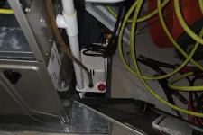 Thumbnail for AC Cooling Repair in Atlanta 30318 by The Air Company. Furnace system with PVC pipes, drainage pump, electrical cords, and yellow extension cords on concrete floor.