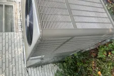 Thumbnail for Outdoor air conditioning unit installed next to a brick house wall with surrounding greenery