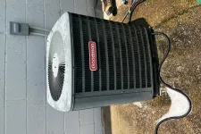 Thumbnail for Goodman air conditioning unit installed outside a building with visible power cable and technician's boots nearby