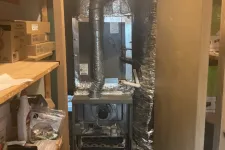 Thumbnail for Heating furnace unit installed in a small utility closet with wooden shelves and stored items.