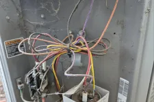 Thumbnail for AC Cooling Repair in Sandy Springs 30328 by The Air Company of GA. Dusty and cobweb-covered electrical wiring and a Titan Pro capacitor inside a damaged HVAC unit.