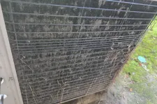 Thumbnail for Dirty and clogged outdoor air conditioner condenser coil covered with dirt, debris, and dried leaves.