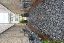 Thumbnail for Narrow side yard between two houses with gravel ground, utility meters, and electrical equipment along the brick wall.