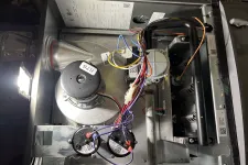 Thumbnail for Interior of a furnace showing motor, wiring, and metal components inside the HVAC unit under light.
