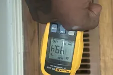 Thumbnail for Hand holding a yellow Fluke 62 MAX IR thermometer measuring temperature near a floor vent showing 49.1°F.