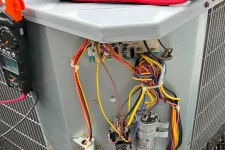 Thumbnail for AC Repair in Roswell 30076 by The Air Company of GA. Outdoor HVAC unit with open panel showing internal wires, capacitor, and electrical connections on mulch ground.