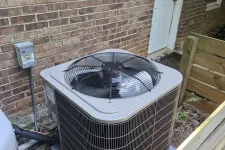 Thumbnail for Outdoor air conditioning unit installed beside a brick house wall, surrounded by a wooden fence.