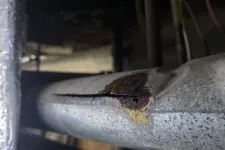 Thumbnail for Close-up of a corroded and cracked metal pipe showing rust and damage indoors.