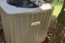 Thumbnail for Outdoor Lennox air conditioning unit surrounded by greenery and pine straw on the ground.