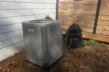 Thumbnail for HVAC Repair, Maintenance and Installation in Roswell by The Air Company of GA. Outdoor Lennox air conditioning unit next to white house wall and wooden fence in a yard covered with dry leaves.
