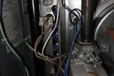 Thumbnail for Residential AC Cooling Repair in Atlanta 30318 by The Air Company.  Inside view of furnace electrical wiring and components with various colored wires and metal pipes.